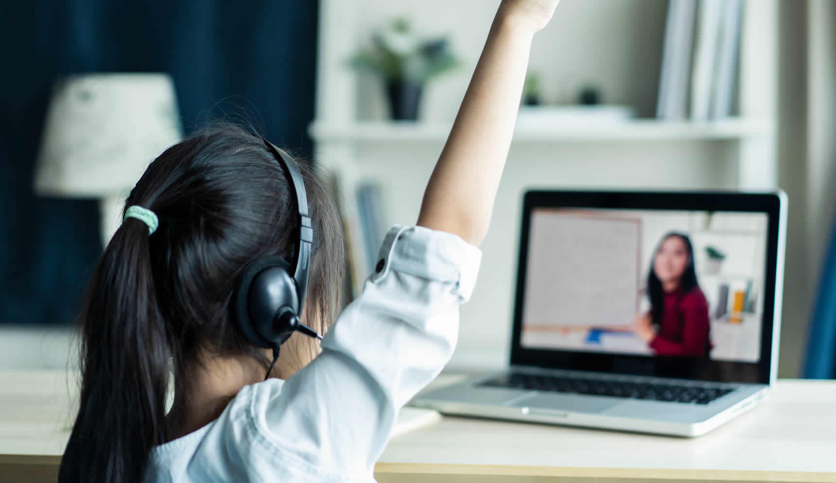 Student raising hand in front of laptop